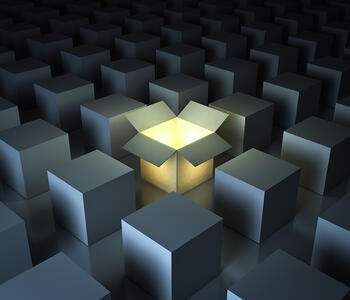 A computer-generated image of some grey boxes in a grid formation. A box in the center is open on top like a package and glowing.