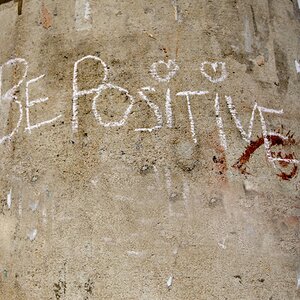 White chalk on concrete pillar with text reading "Be Positive"